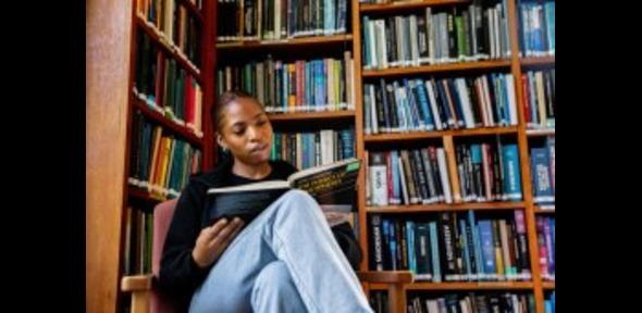 Young woman reading in front of library shelves Young woman reading in front of library shelves